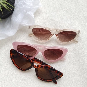 Retro cat-eye sunglasses in champagne, matte pink, and tortoiseshell on a white texture