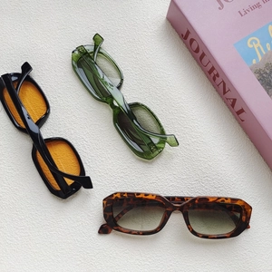 Flat lay of vintage rectangular sunglasses in orange, green, and tortoiseshell frames