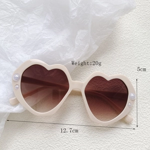Detailansicht der herzförmigen Sonnenbrille mit Perlenakzenten und braunen Verlaufsgläsern