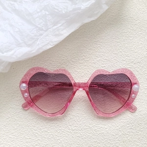 Detail der herzförmigen Kinder-Sonnenbrille in Pink mit Glitzer und Perlenbesatz
