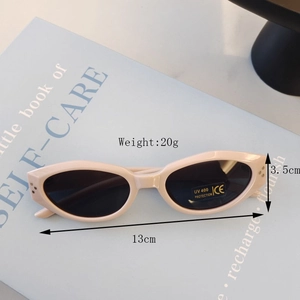 Close-up of retro oval cream sunglasses for kids on a book showing side rivet details