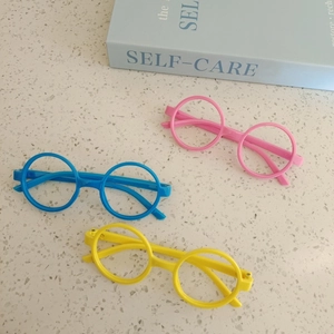 Kids round frame glasses in pink blue and yellow colors on a marble tabletop
