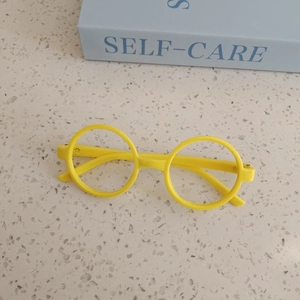 Top view of yellow round frame glasses for kids on stone surface with a blue book