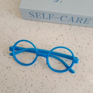 Detail of round bright blue kids fashion glasses frame without lenses on a stone surface