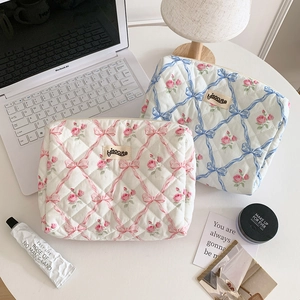 Trousses de maquillage matelassées à fleurs rose et bleu sur un bureau de travail