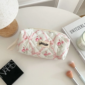 Détails de la trousse de maquillage matelassée avec nœuds roses et motifs floraux