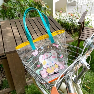 Detailed view of clear PVC tote with cartoon bears in a bicycle basket outdoors