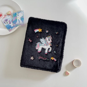 Detail of plush black notebook cover with embroidered unicorn and soft texture