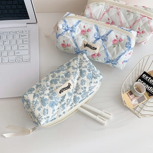 Detail of floral quilted pencil case with ribbon zipper and woven brand label