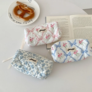 Quilted floral pencil cases with ribbon details in pink and blue displayed on a desk