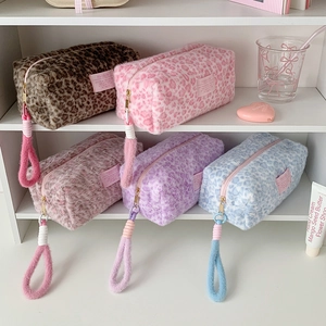 Set of five colorful plush leopard print makeup bags with soft handles displayed on a shelf