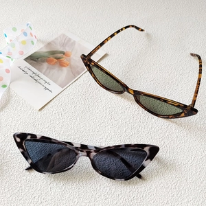 Retro cat-eye sunglasses with tortoiseshell and marble patterns on a textured background