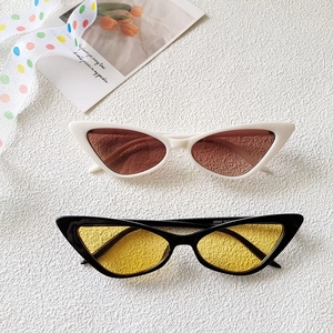 Flat lay of cat-eye sunglasses in white-brown and black-yellow on a textured background