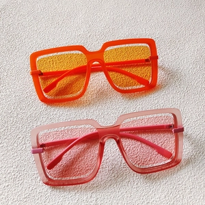Detail view of bold oversized square sunglasses in vibrant orange and soft pink colors