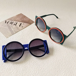 Detail of color-block round frame sunglasses with gradient lenses on a fashion magazine