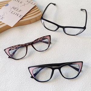 Flat lay of retro cat-eye kids glasses in black, tortoiseshell and pink on white texture