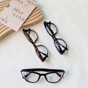 Three cat-eye kids glasses frames in black, leopard, and blue tortoise on a wooden tray