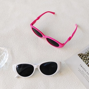 Vue à plat de lunettes de soleil œil de chat roses et blanches sur fond beige