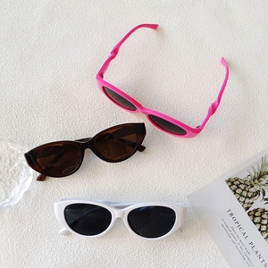 Gros plan de lunettes de soleil ovales rétro en rose, marron et blanc, cadres brillants