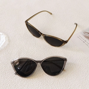 Detail view of cat-eye frames in amber and smoky gray resin on a textured background