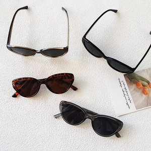 Flat lay of cat-eye sunglasses in black, tortoiseshell, grey and olive on a white textured surface