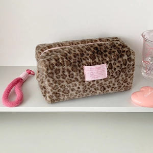 Close-up of plush leopard print makeup bag with pink zipper pull and brand patch