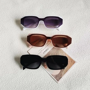 Trois lunettes de soleil rectangulaires rétro en blanc, rose et noir sur fond gris