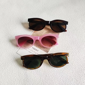 Vintage rectangle wide sunglasses in black, pink, and tortoiseshell on a white textured backdrop