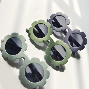 Detailed top view of flower-shaped children's sunglasses in Morandi colors with leaf shadows