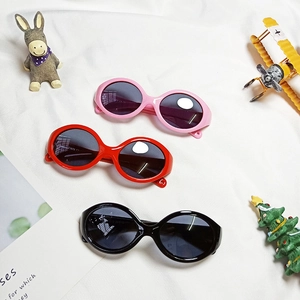 Flache Ansicht von polarisierten Baby-Sonnenbrillen in Pink, Rot und Schwarz auf Stoff