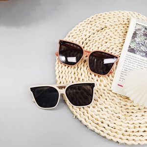 Polarized square frame kids sunglasses in pink and ivory on a minimalist woven background
