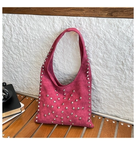 Detail of rose red suede tote bag featuring silver rivet studs on textured handle