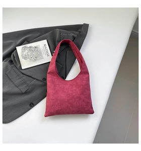 Detail shot of a hot pink suede hobo bag with minimalist design on a sleek white surface