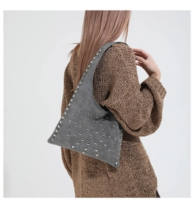 Détail du sac bandoulière triangulaire gris avec rivets en métal sur tissu suédé doux