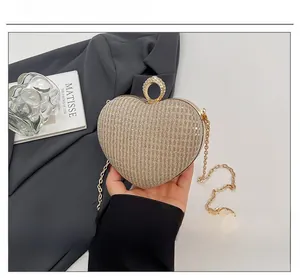 Détail de pochette de soirée en forme de cœur avec poignée en diamant et chaîne dorée