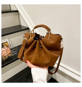 Detailansicht der braunen Falten-Beuteltasche mit goldenem Ringgriff und Ledertextur
