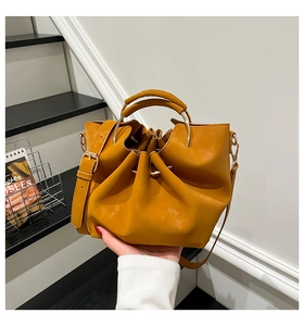 Detail der ingwerfarbenen Leder-Beuteltasche mit Falten und goldenem Ringgriff