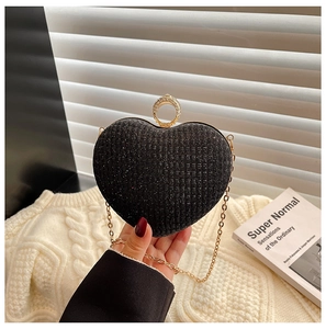 Détail de la pochette cœur pailletée noire avec poignée strassée et chaîne dorée