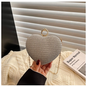 Détail d'une pochette coeur à paillettes argentées avec fermoir strass et chaîne dorée