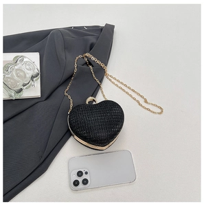 Vue détaillée de la pochette cœur pailletée noire avec chaîne dorée et téléphone pour l'échelle