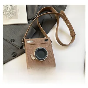 Detail view of a vintage camera-shaped crossbody bag with brown textured finish and strap