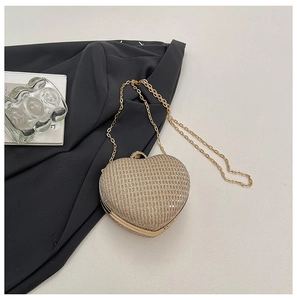 Détail macro d'une pochette dorée en forme de cœur avec une élégante bandoulière chaîne