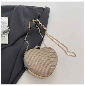 Détail d'une pochette cœur à paillettes dorées avec bandoulière chaîne et fermoir strass