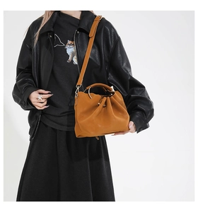 Détail d'un sac seau plissé gingembre avec poignée en anneau métallique et cuir souple