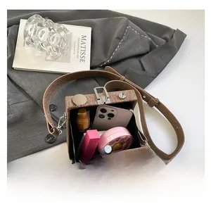 Interior view of brown twill box bag showing storage for phone, lipstick, and cosmetics