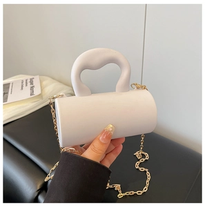 Détail du mini sac cylindrique blanc en acrylique avec poignée et chaîne en métal doré