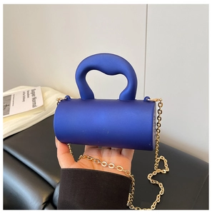 Détail du sac cylindre en acrylique bleu avec poignée ronde et bandoulière chaîne dorée