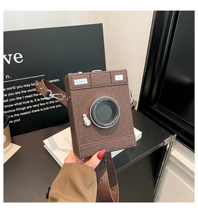 Close-up of a vintage camera-shaped brown leather crossbody bag with lens detail