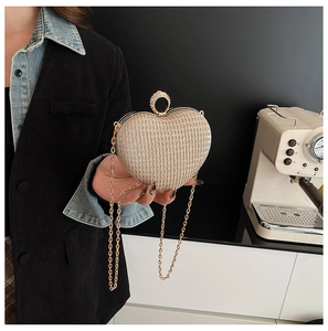 Gros plan d'une pochette coeur doré champagne avec strass scintillants et fermoir anneau