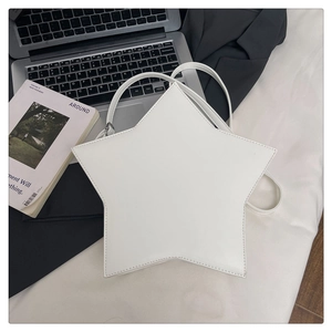 Flat lay of white star-shaped shoulder bag on a desk with laptop and magazine